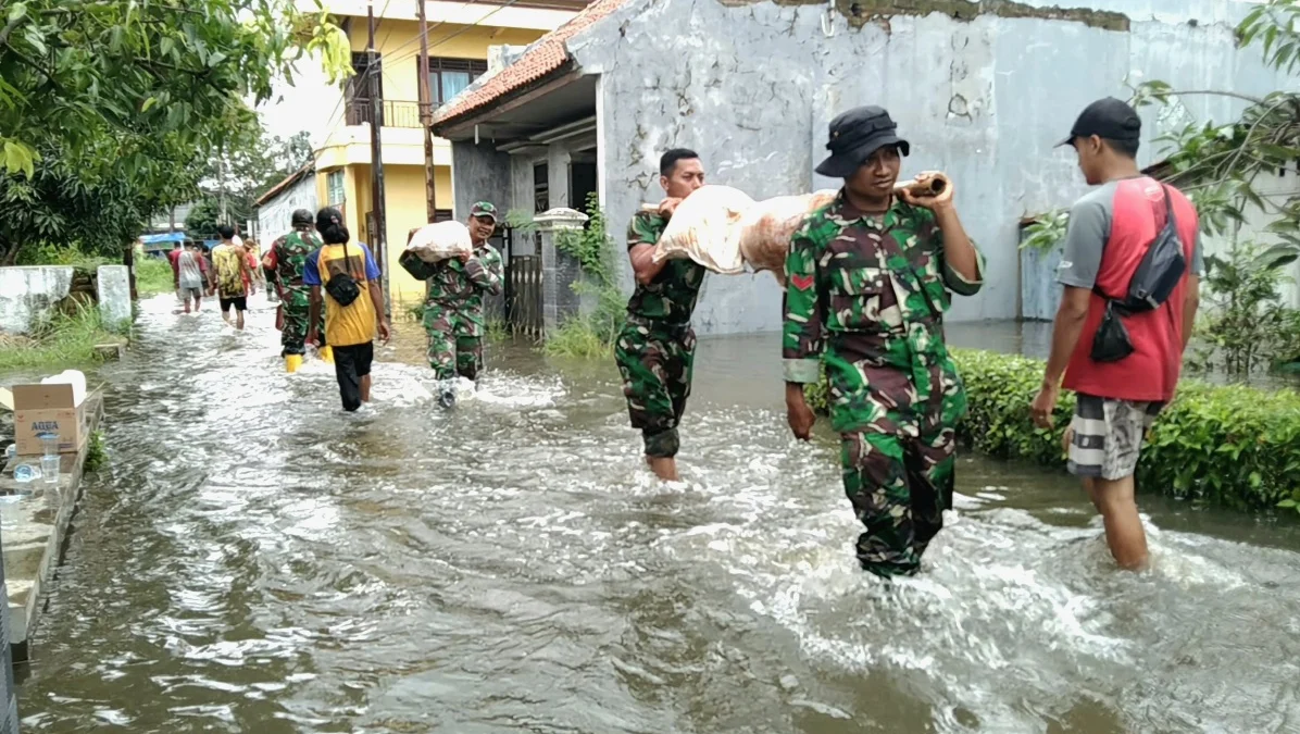 TNI bersama bpbd dan warga gotong royong membuat tanggul darurat di Sungai Meduri