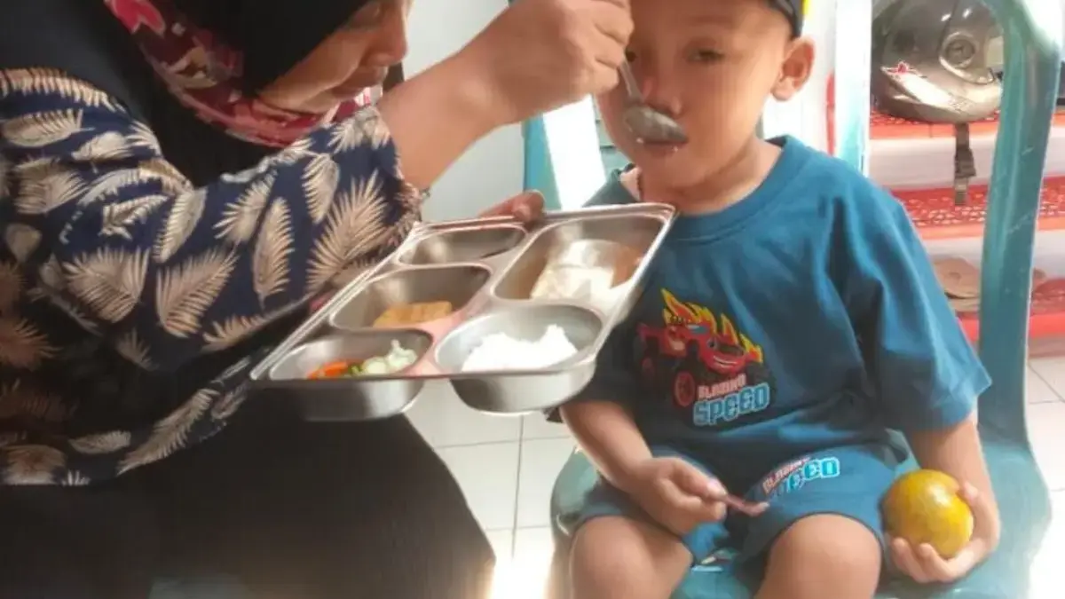 Seorang balita penerima manfaat program MBG tengah lahap menyantap makanannya.